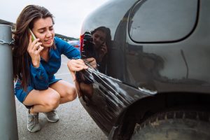 woman looking at scratch on side of car