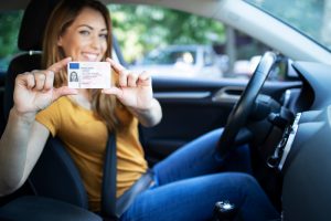 woman in car holding license